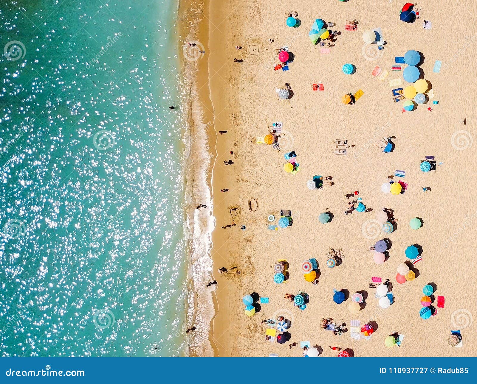 aerial view from flying drone of people crowd relaxing on beach