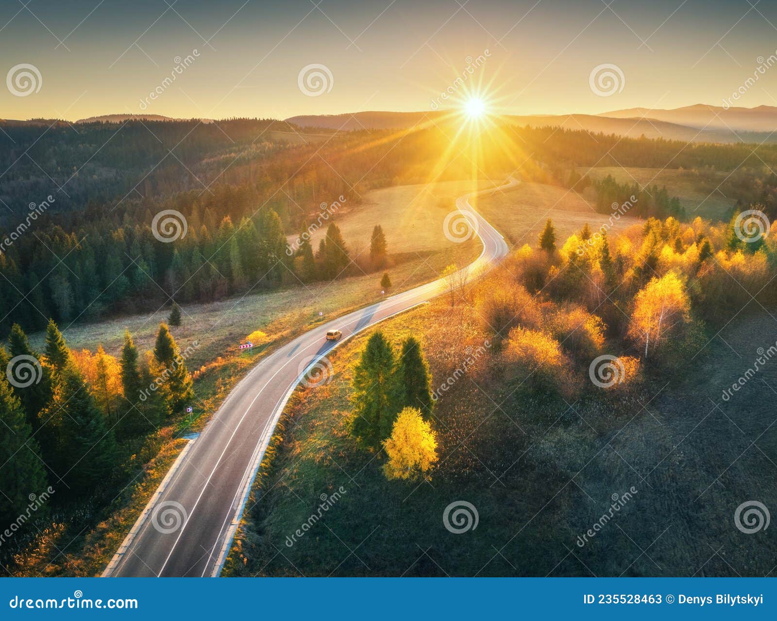 aerial view of mountain road in forest at sunset in autumn