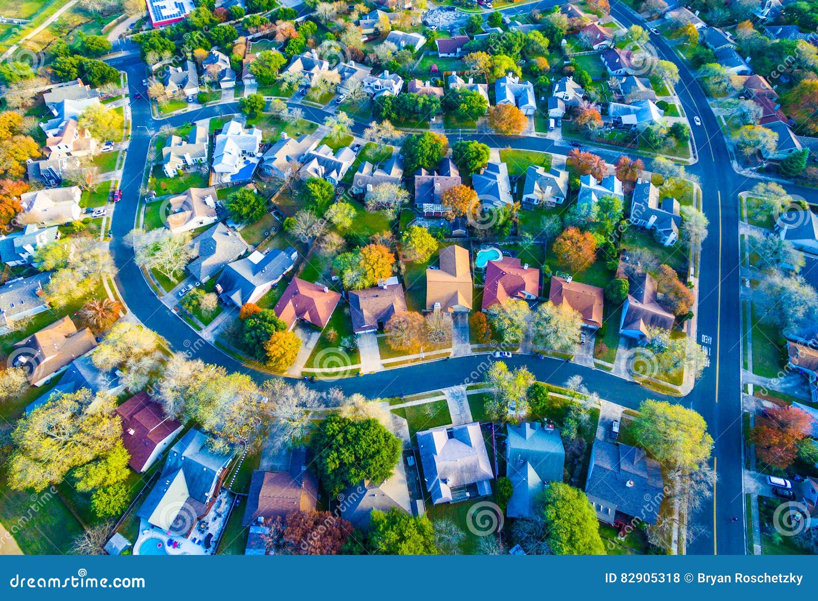 aerial view over modern suburb home community with fall colors curved streetes