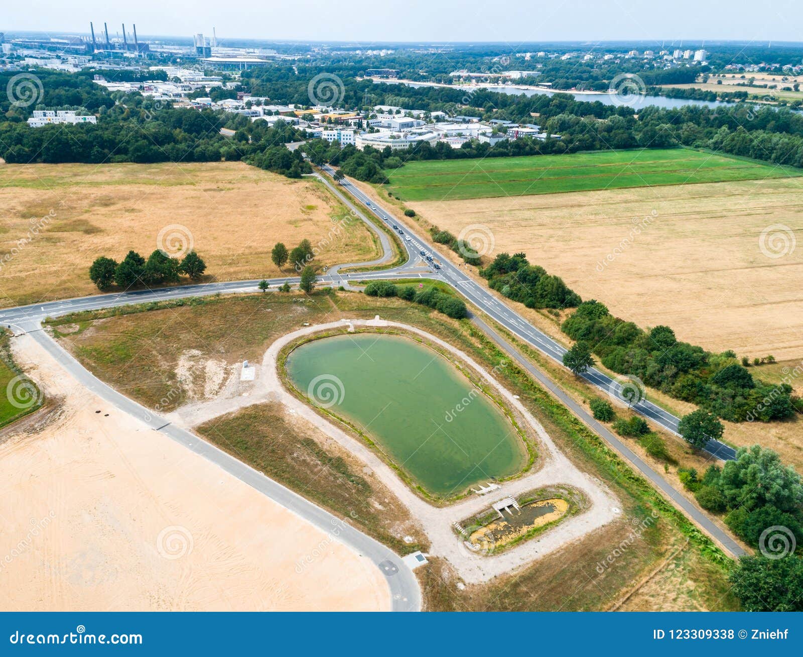 aerial view of a rain retention basin at the edge of a new development, taken oblique
