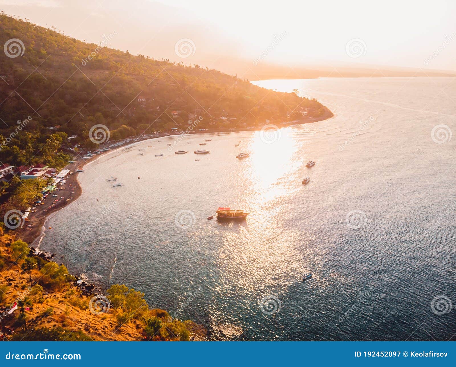aerial view of sea with mountains and local boats in amed, bali with sunset lights