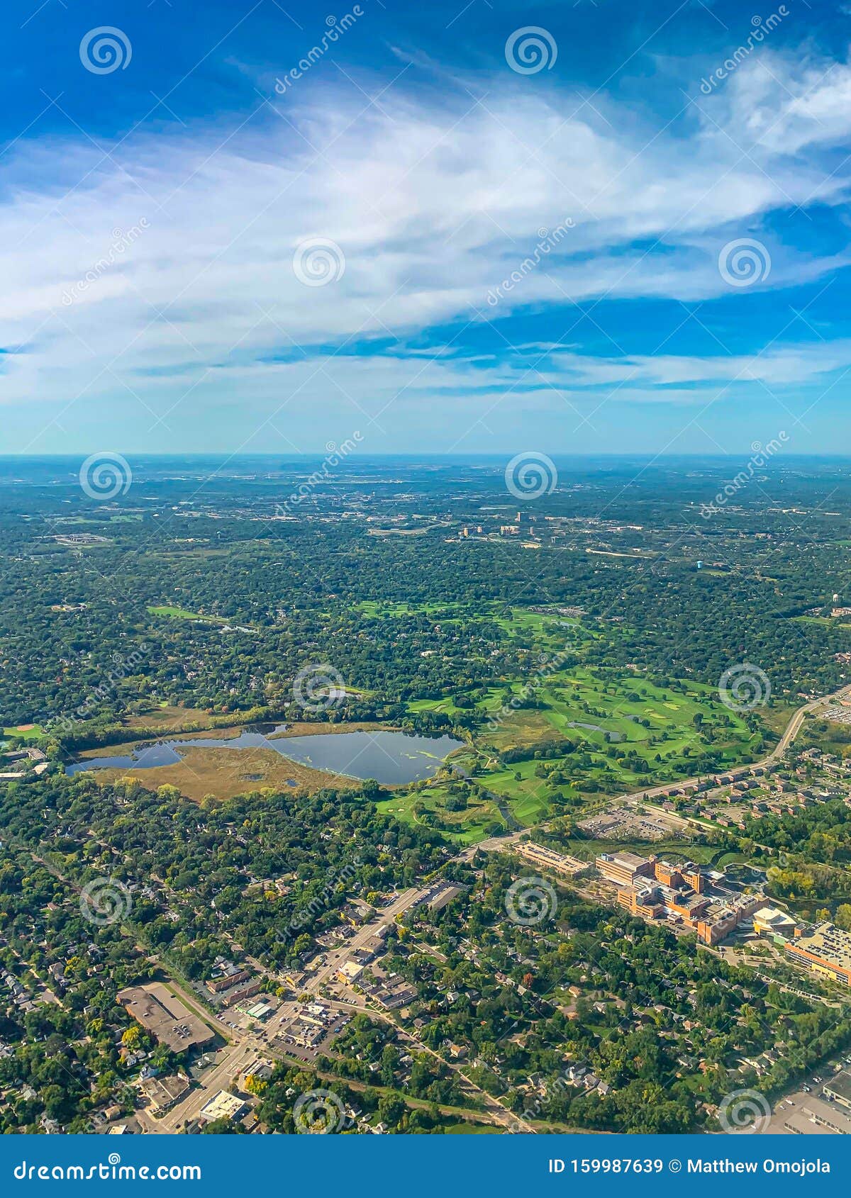 aerial view of several golf courses in a densely forested urban development