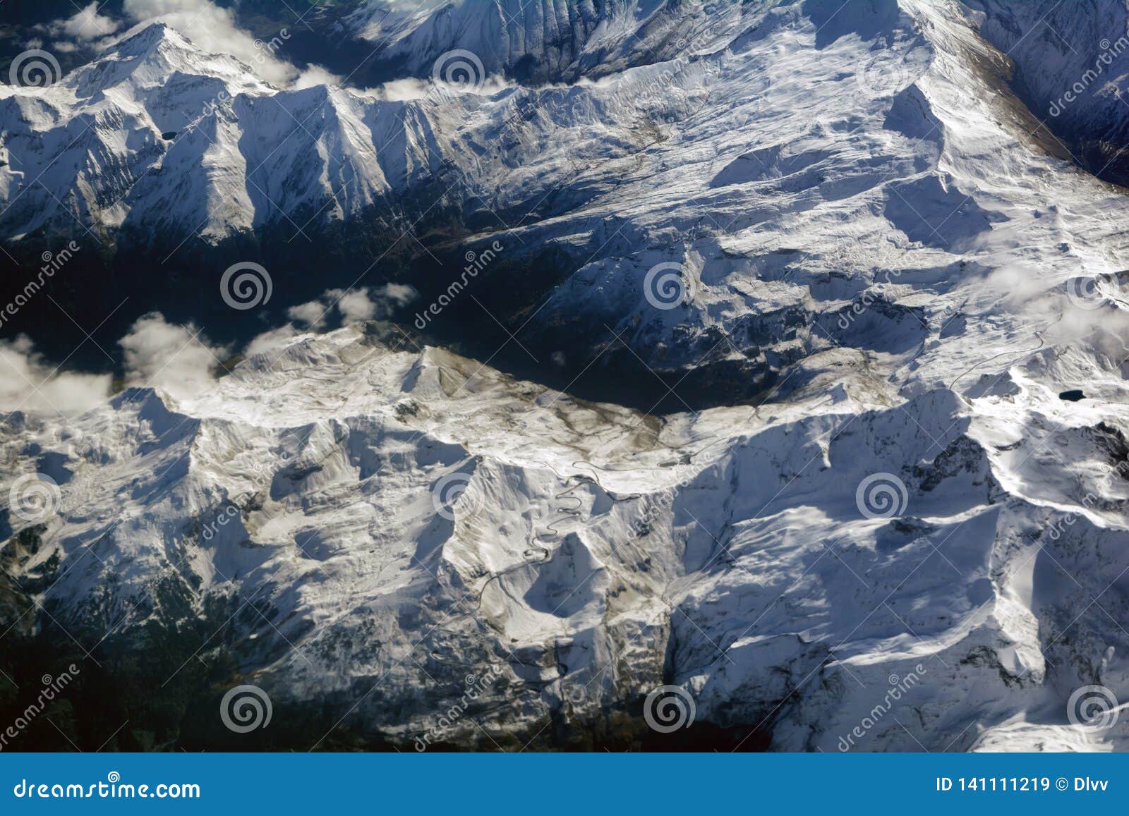 Aerial View of Snowy Mountains Peaks and a Winding Serpentine, Road, Opposite the Sunlight Image - of horizontal, background: 141111219