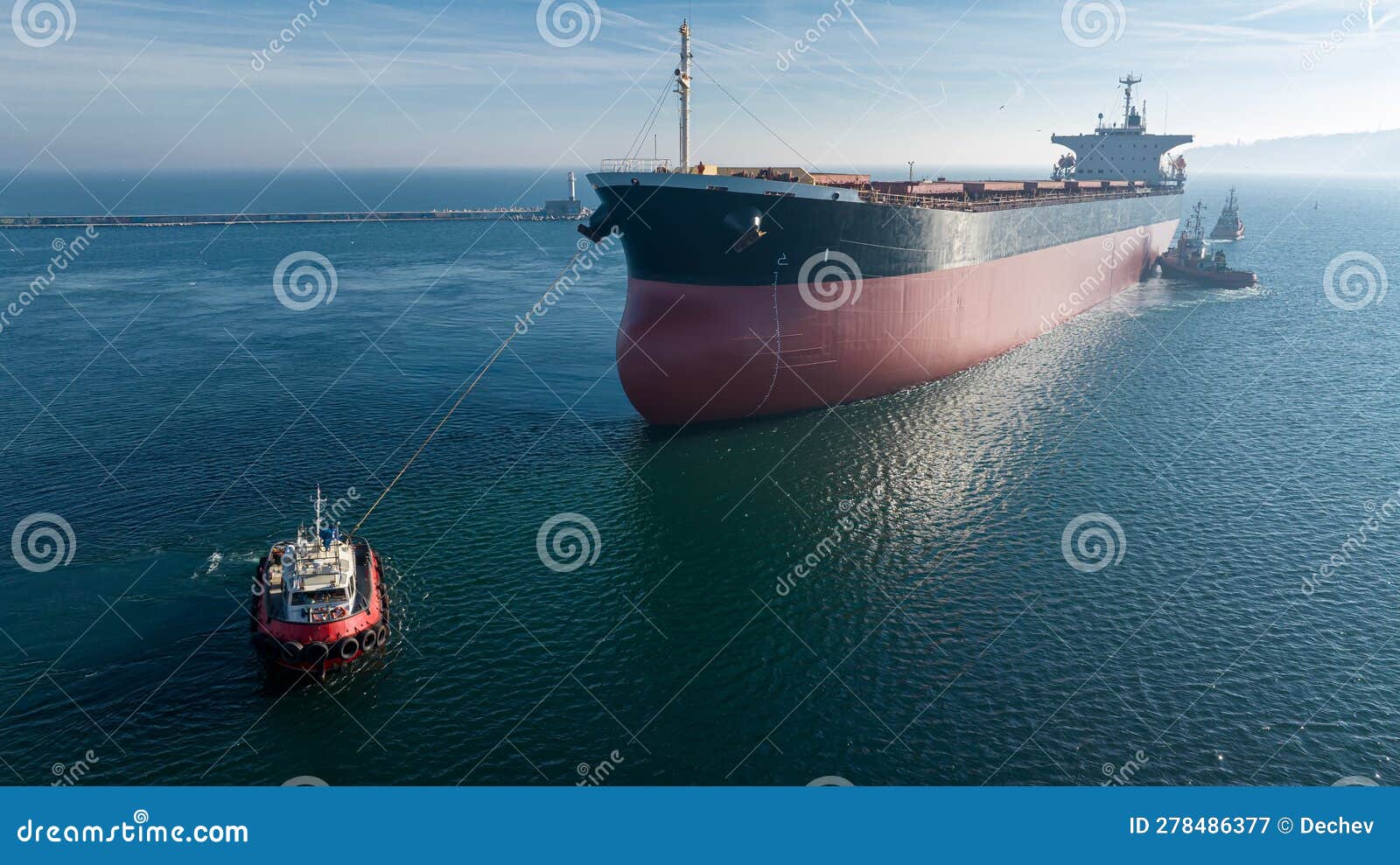 aerial view of tug boat assisting big cargo ship. large cargo ship enters the port escorted by tugboats