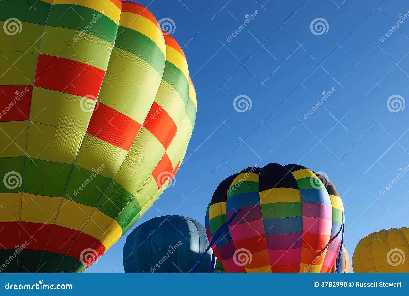 Un primo piano di parecchi aerostati di aria calda colourful ha impostato contro un cielo blu libero.