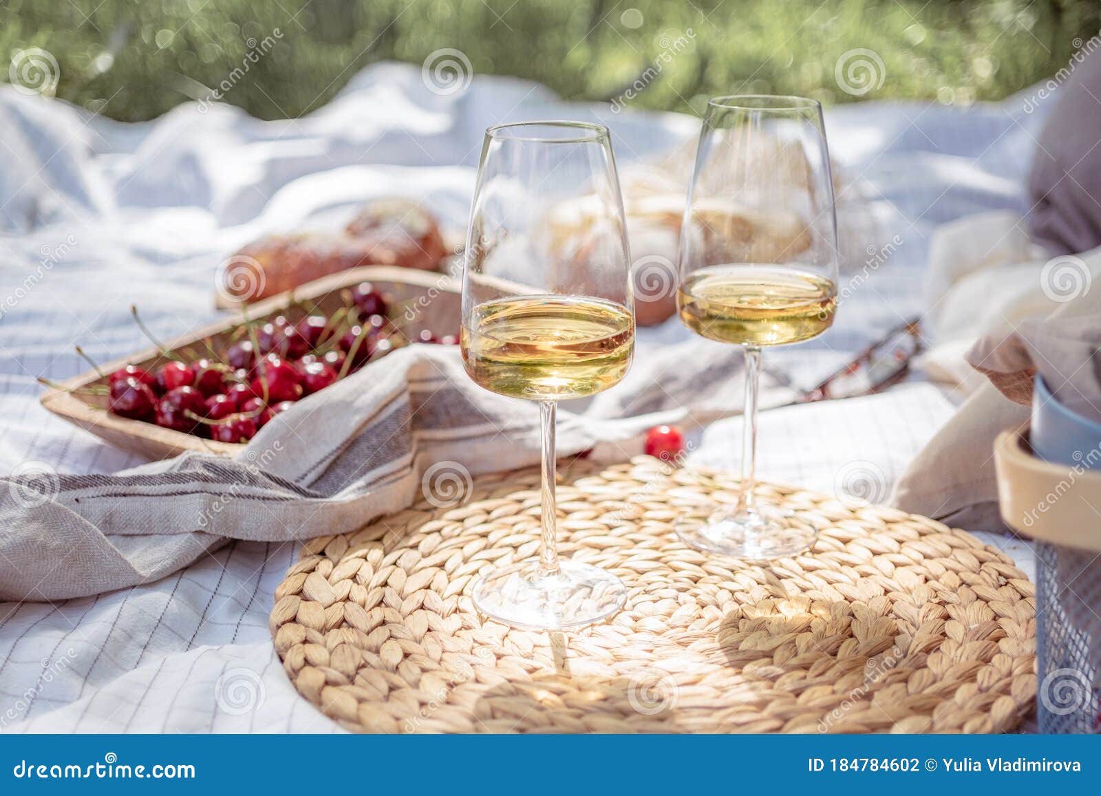 Aesthetic picnic outdoors with wine glasses bread berries and flowers.  Rustic picnic with neutral tones colours. Stock Photo by  ©lamapacas.gmail.com 378420028