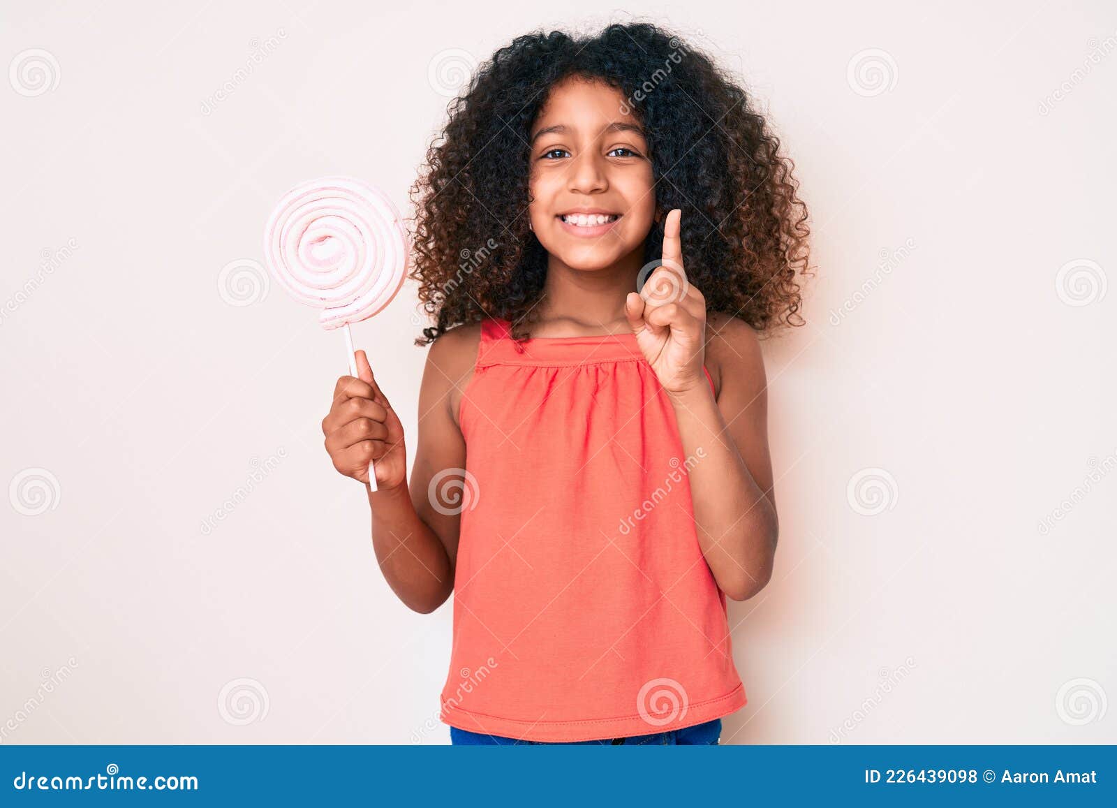 African American Child with Curly Hair Holding Lollipop Smiling with an ...