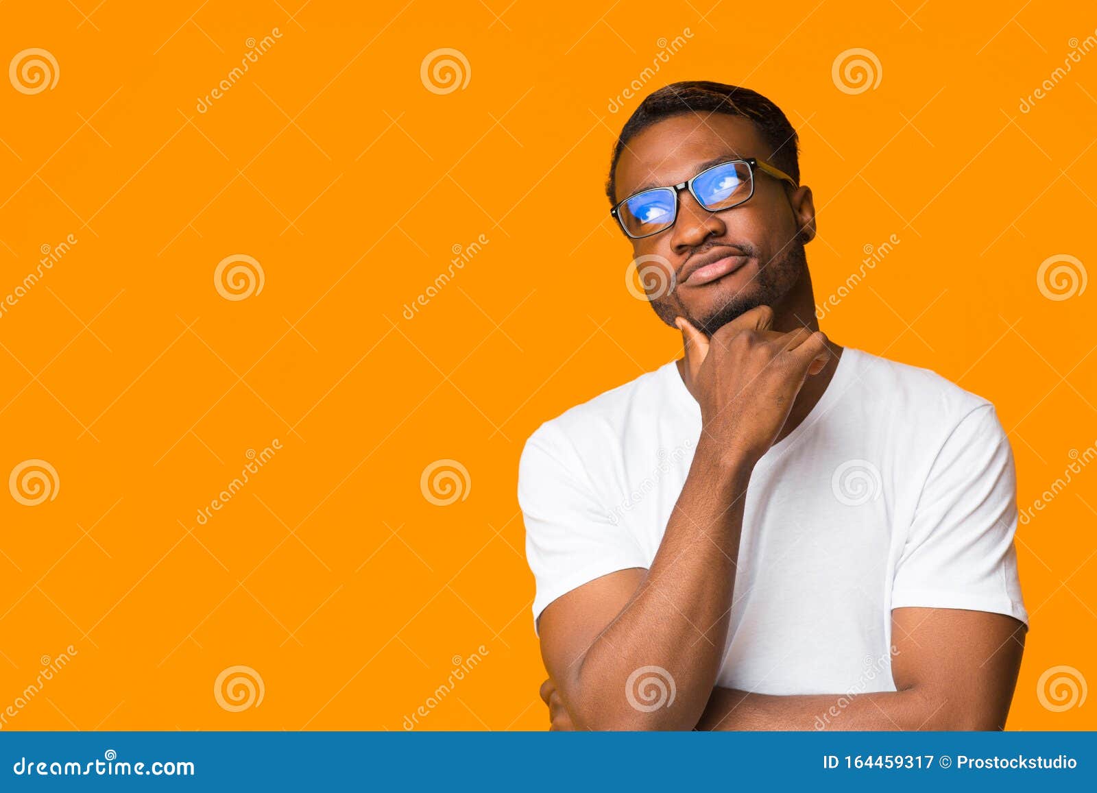 african american guy thinking touching chin standing over orange background