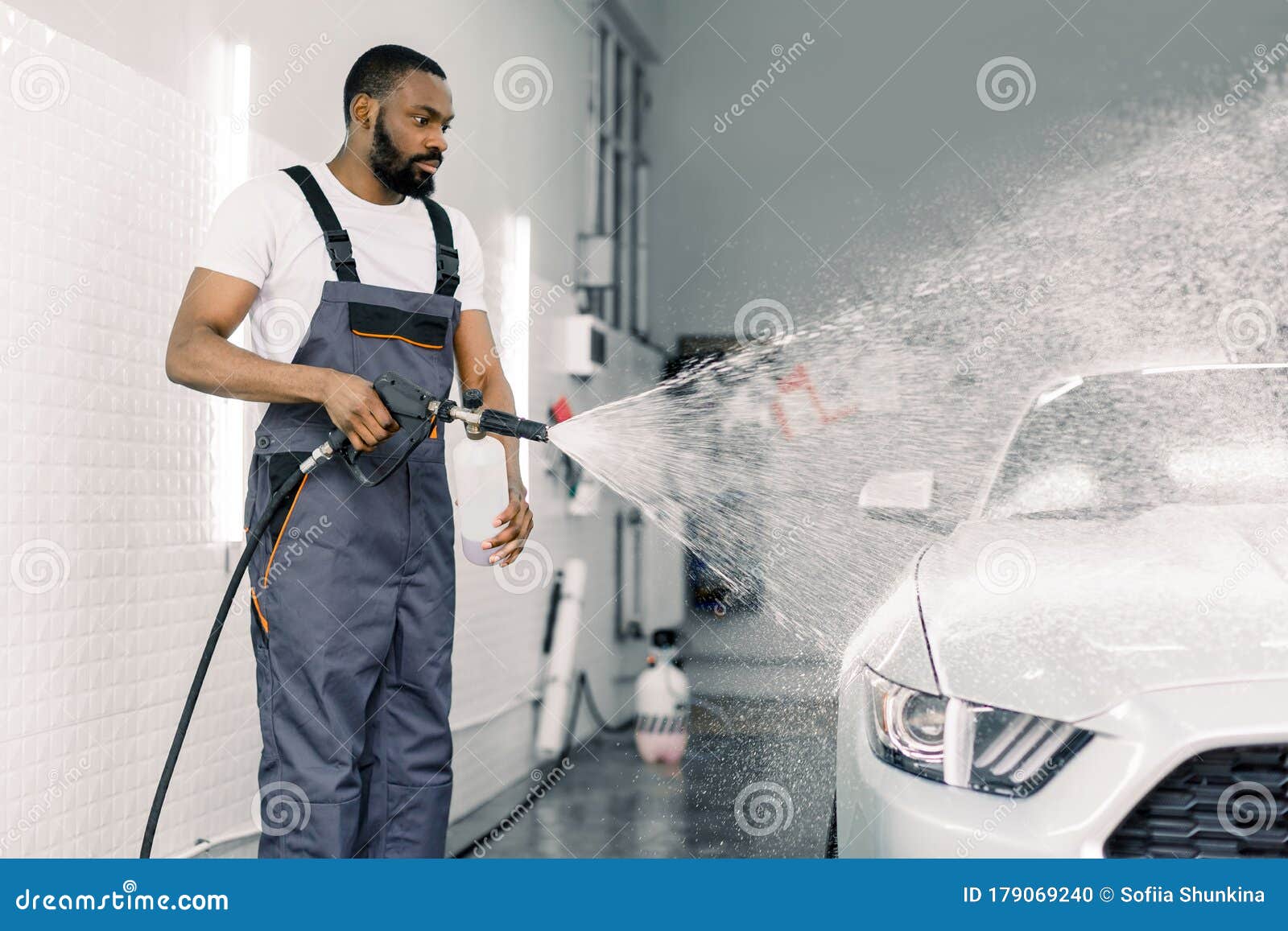 African American Man, Car Wash Worker Is Spraying Cleaning Foam To A