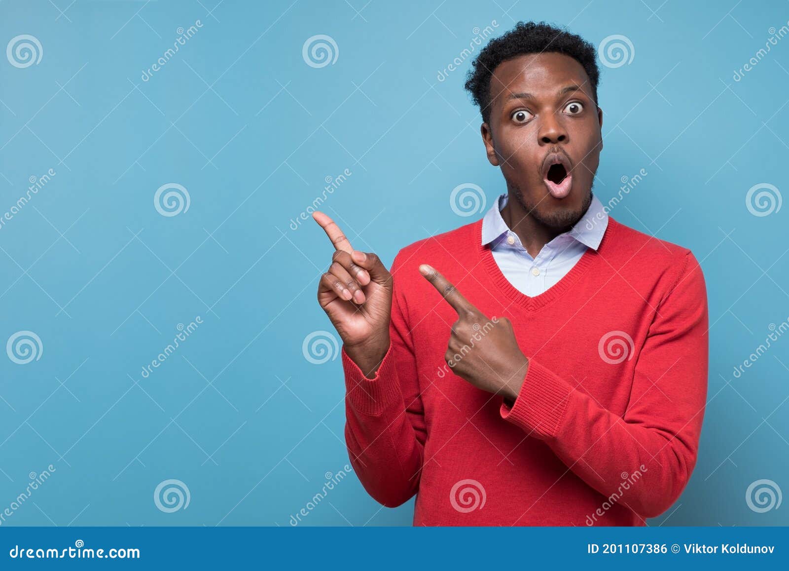 African American Man Opening Mouth Widely, Pointing Aside on Blue Wall ...