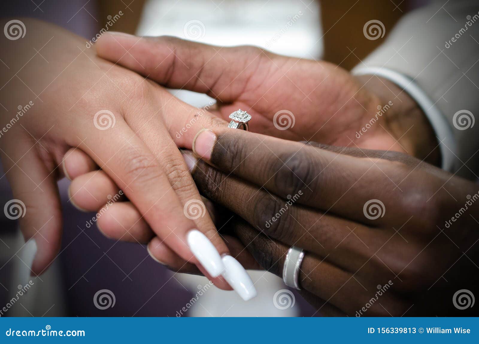 interracial couple exchanging wedding rings at marriage ceremony
