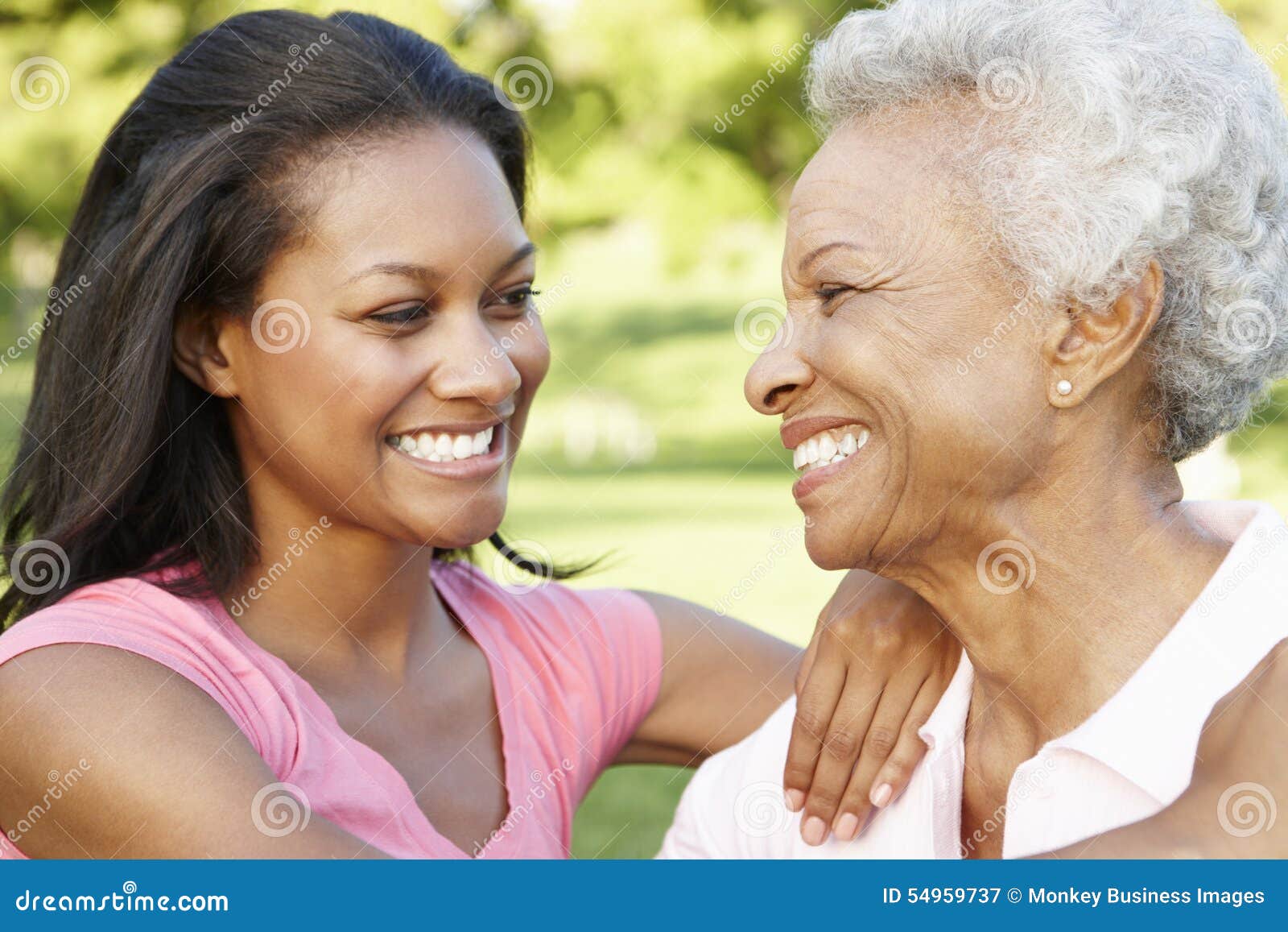 african american mother and adult daughter relaxing in park