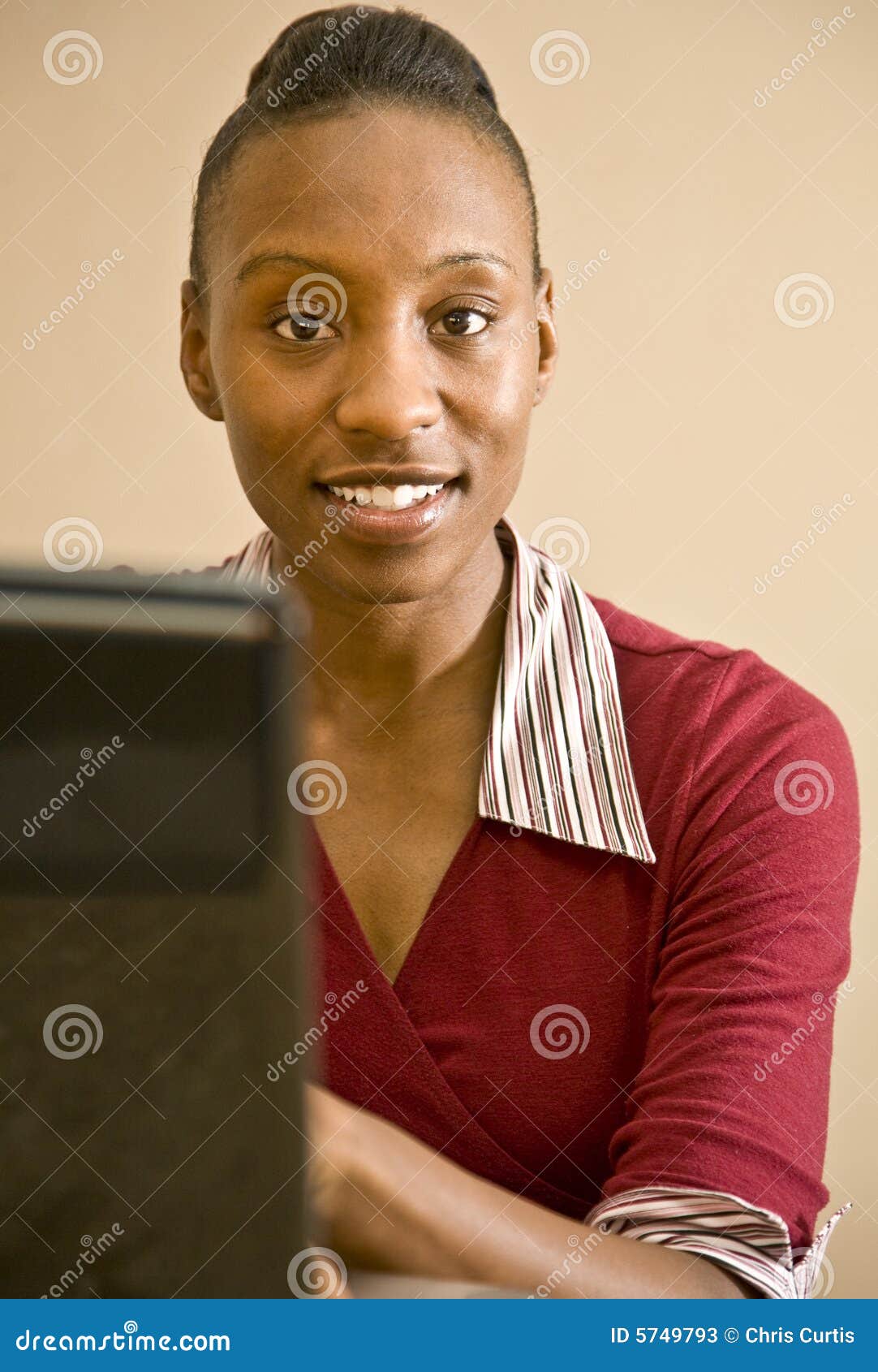 An attractive African American office worker, IT specialist or business woman seated at a computer.