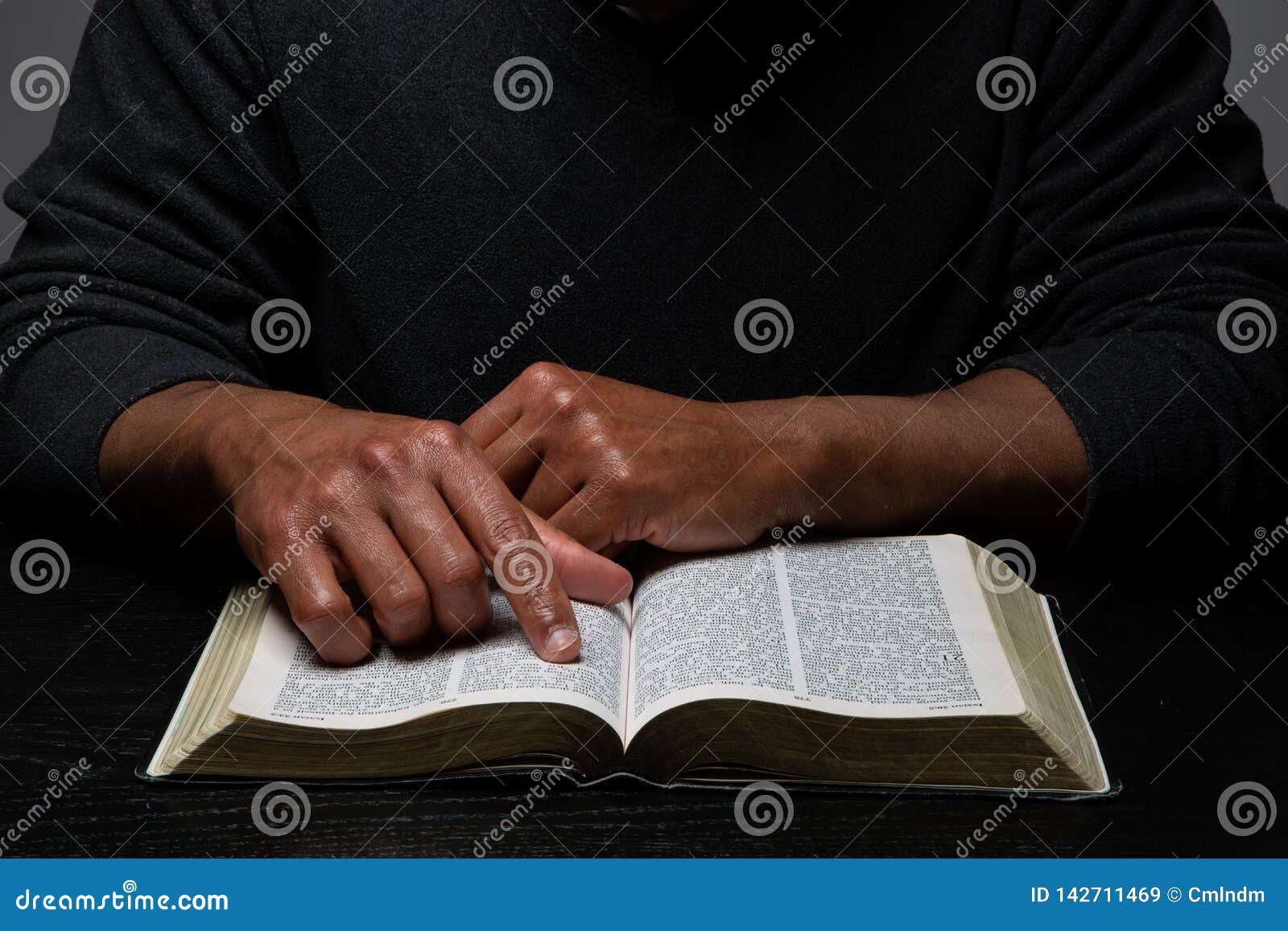 african american person studying the bible in dark room