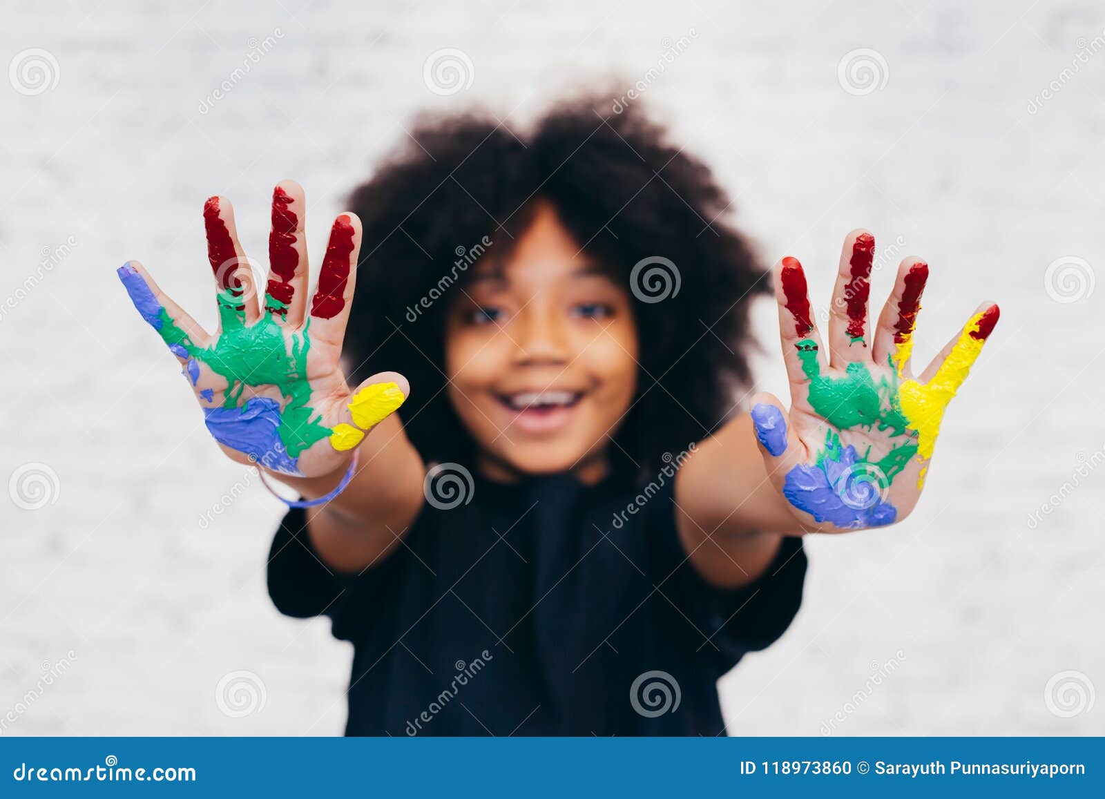 african american playful and creative kid getting hands dirty with many colors