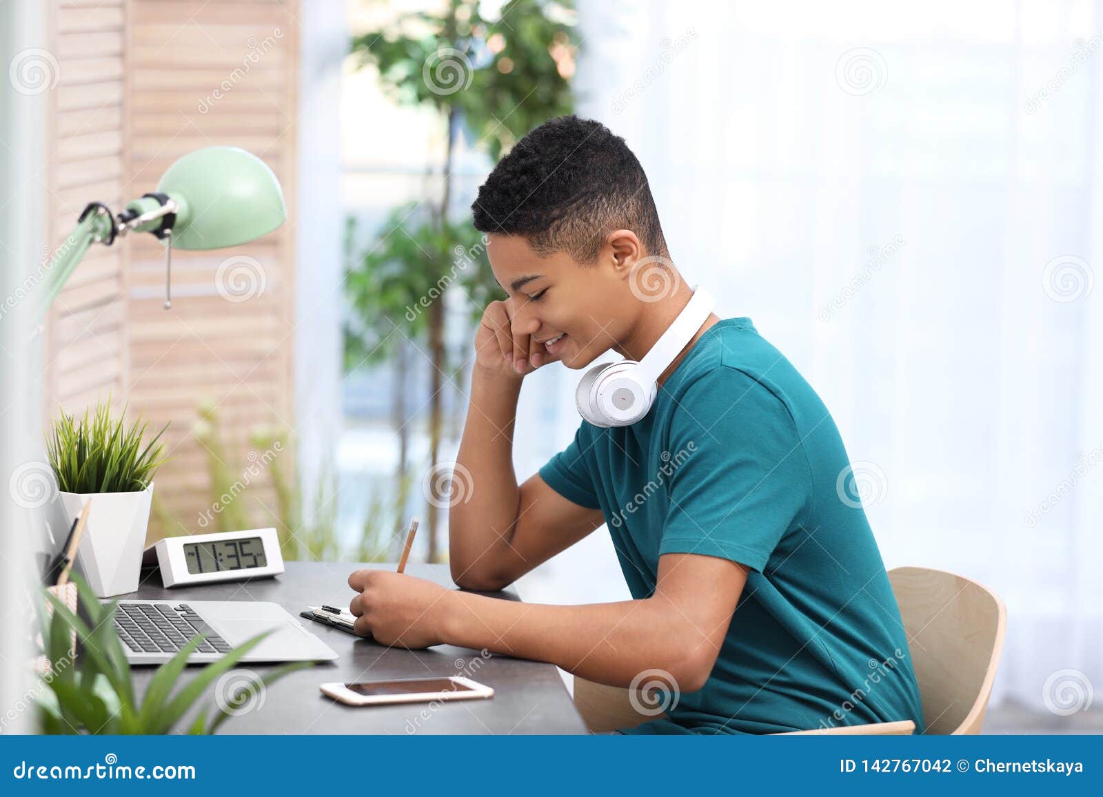 African American Teenage Boy Doing Homework At Table Stock Photo