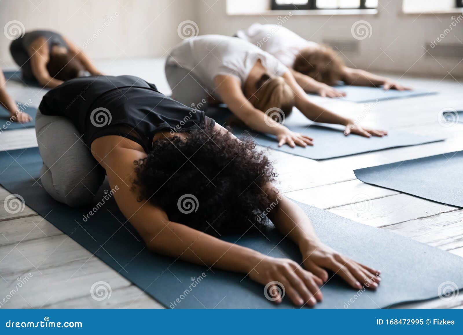 african american woman doing balasana exercise at group yoga lesson