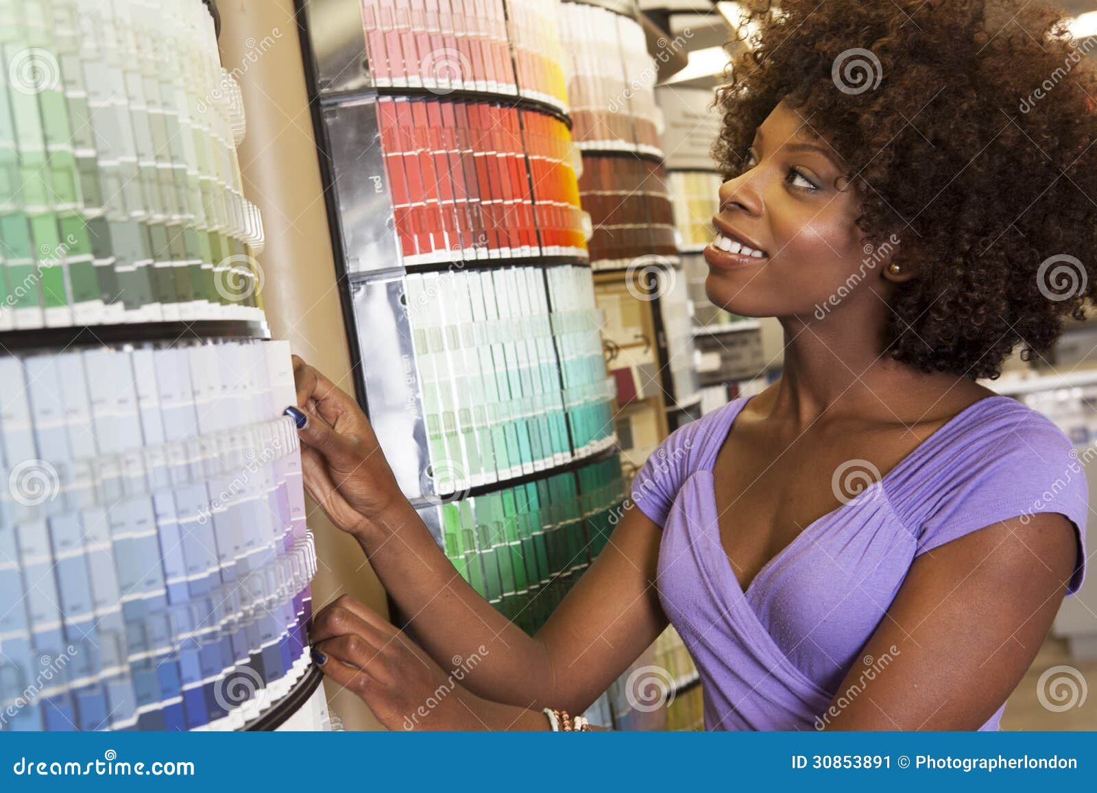 african american woman looking at paint swatches at hardware store
