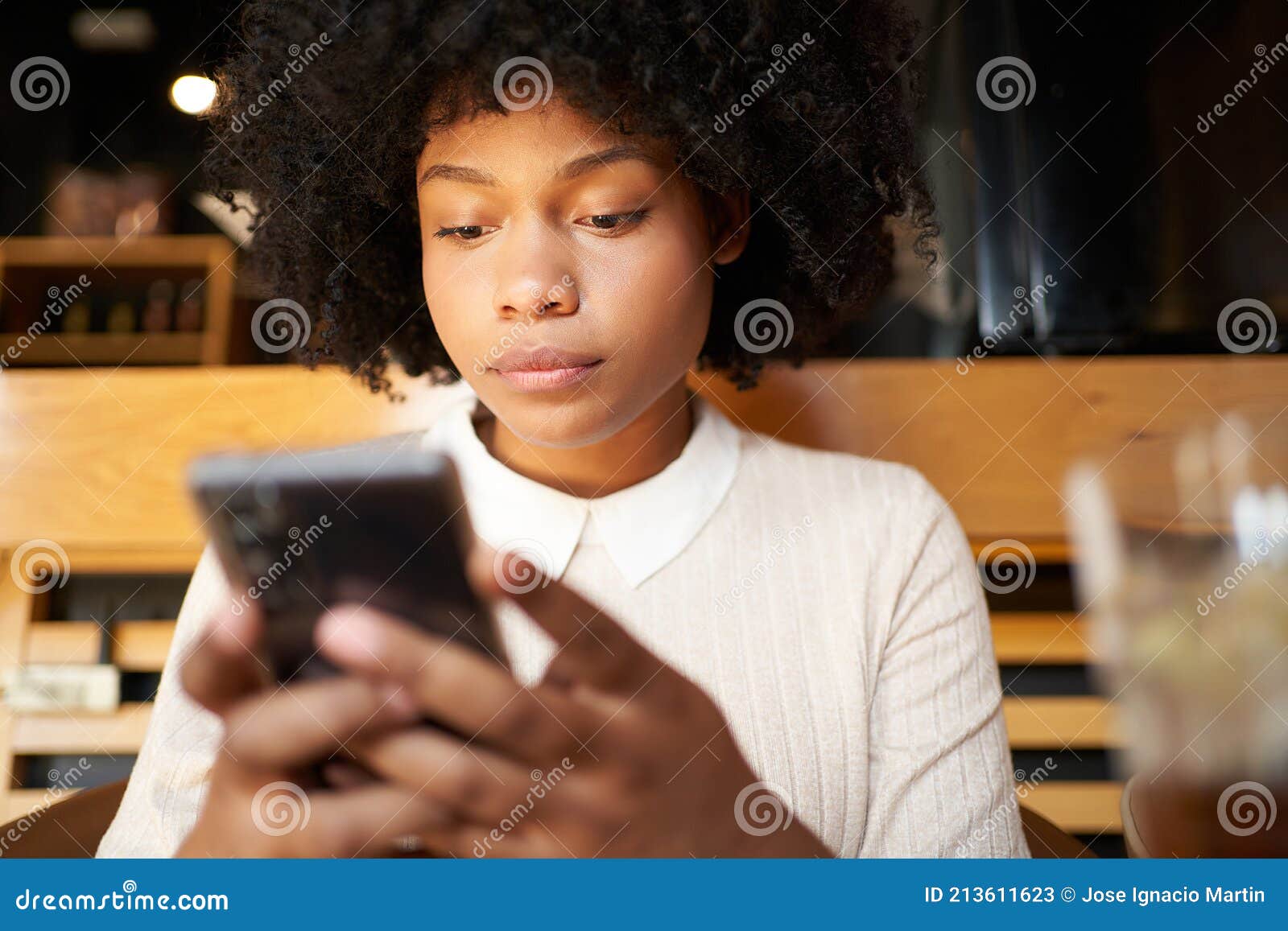 African American Woman Using a Cell Phone in a Coffee Shop. Latina ...