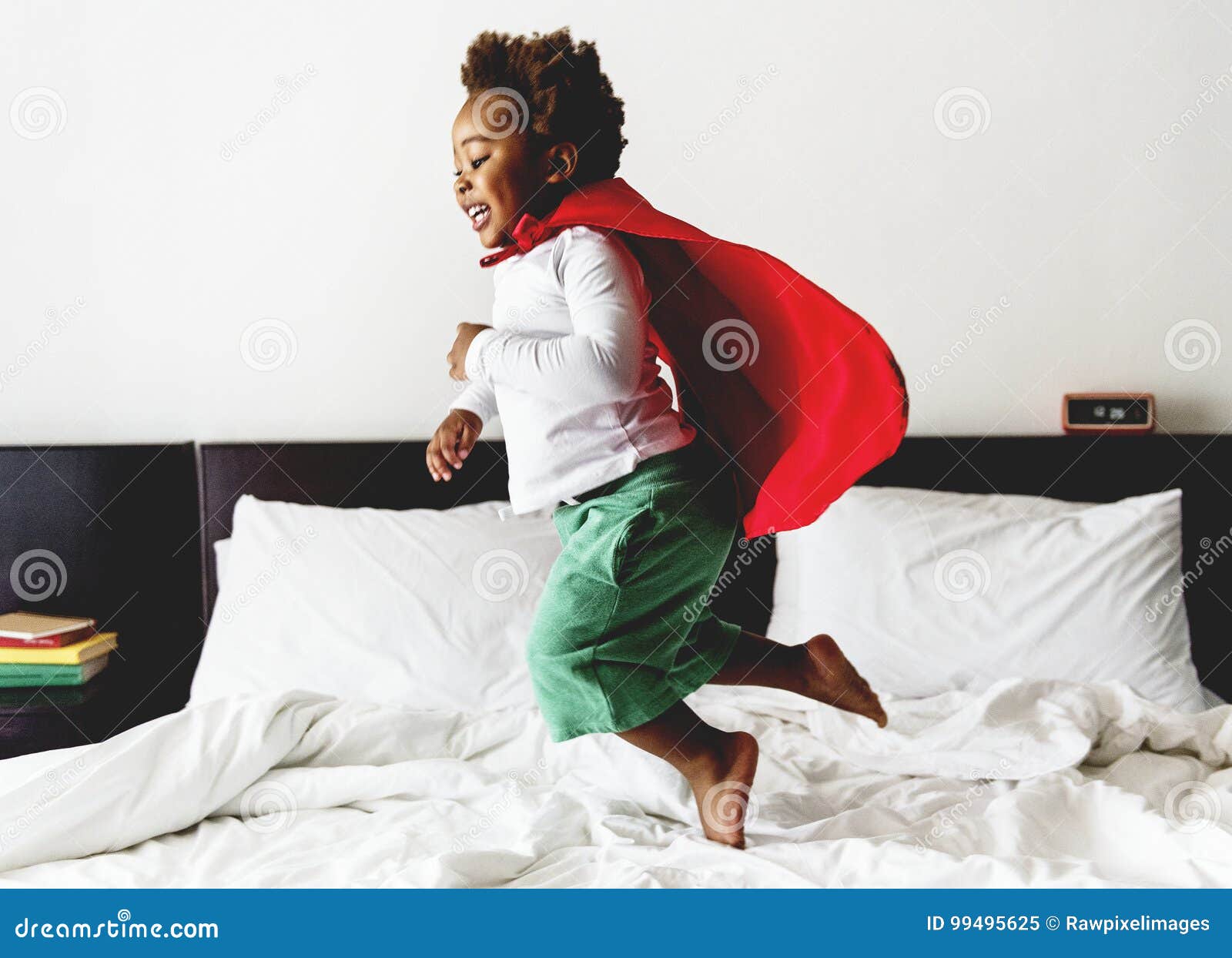 african descent kid jumping on the bed with robe