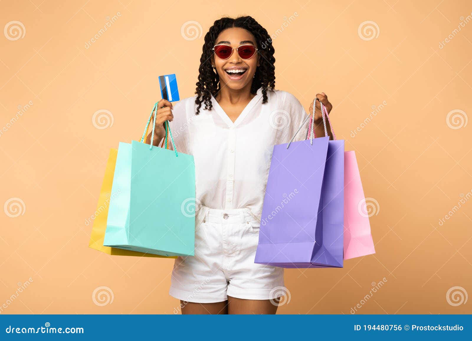 african girl on shopping holding credit card, beige studio background