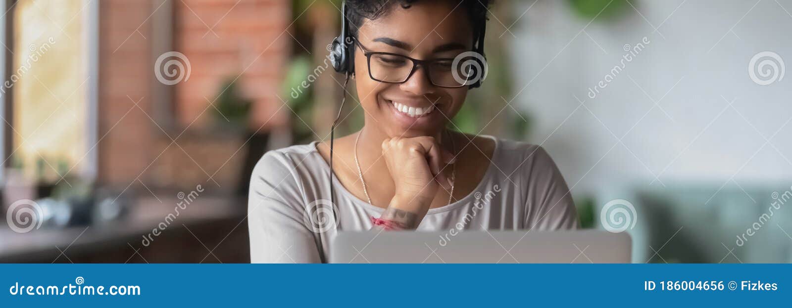 smiling african girl wear headphones watch online webinar use laptop
