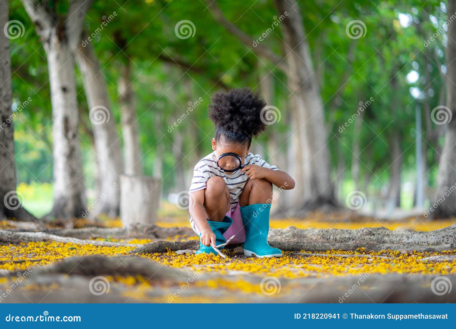 african little girl exploring in the woods and looking for insects, child playing in the forest with magnifying glass. curious kid