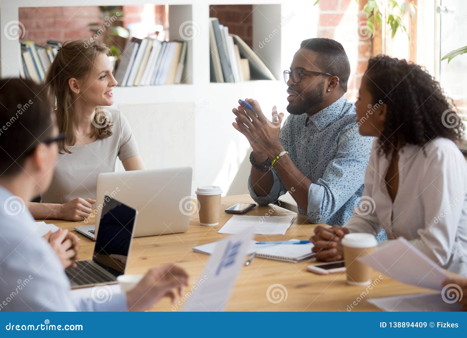 african male employee speaking sharing ideas at diverse team meeting