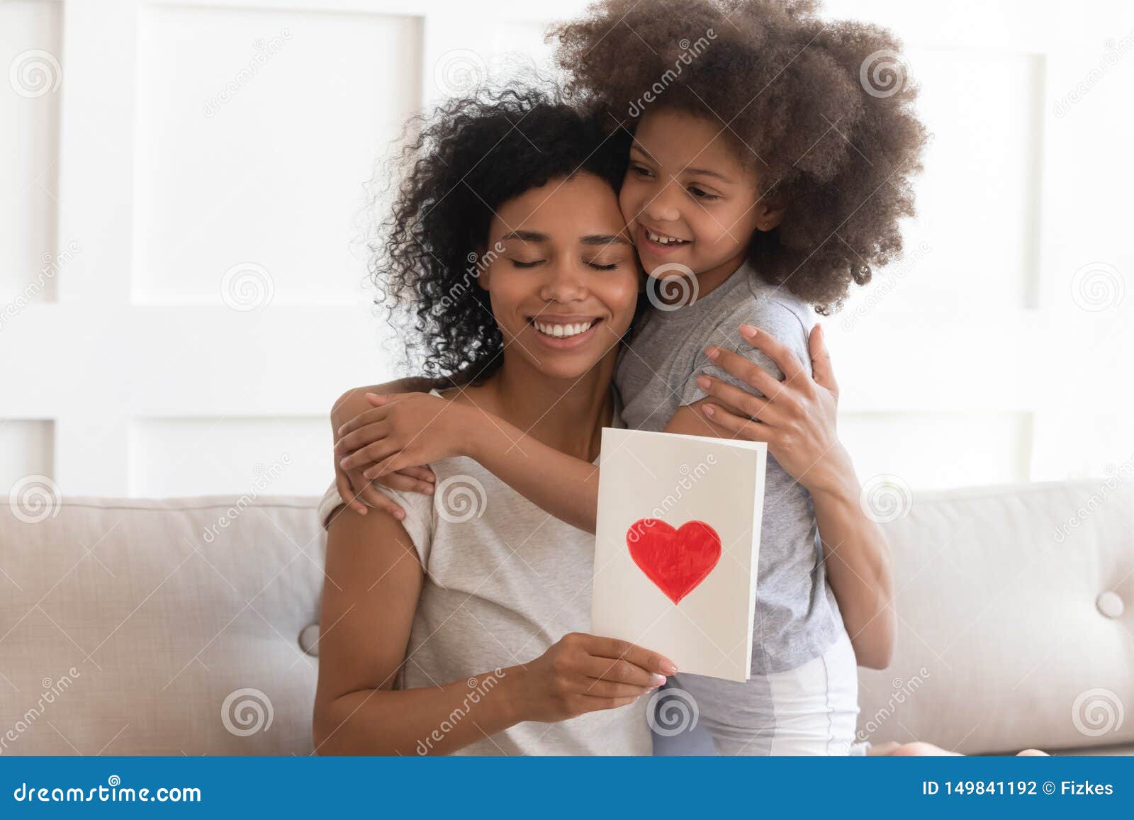african mum hugging daughter holding greeting card on mothers day
