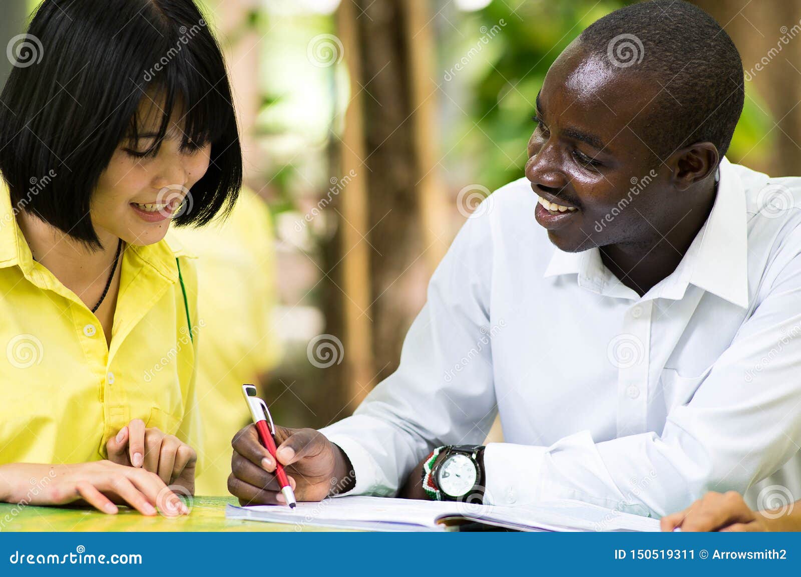 African Teacher Teaching Asian Student about Foreign Languages Stock