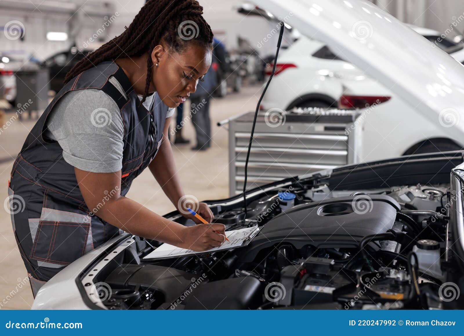 Afrikanische Mechanikerin Bei Der Arbeit Überprüfung Auto Haube Schreiben  Notizen in Tablette Stockfoto - Bild von kontrolle, aufgabe: 220247992