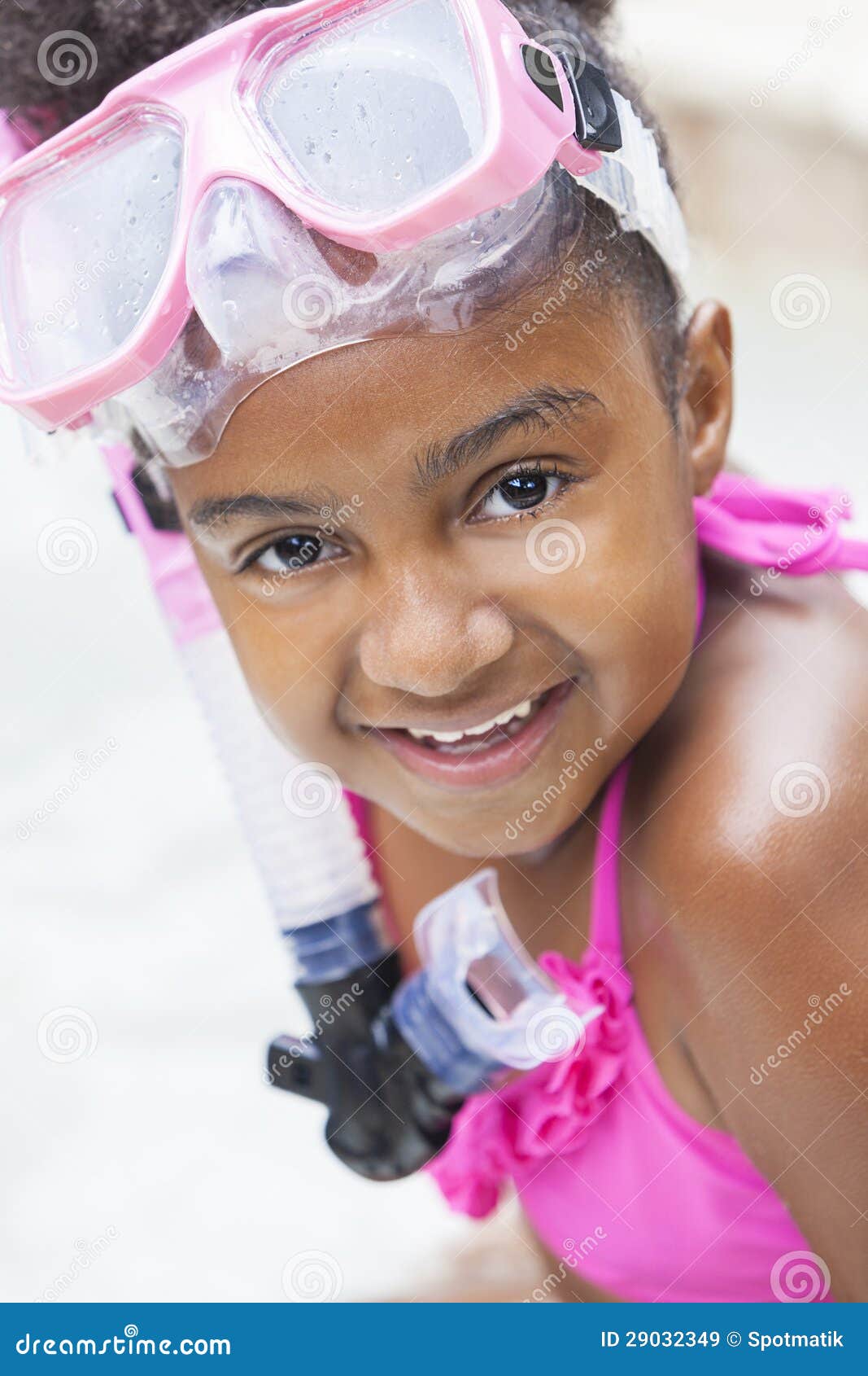 Afroamerikaner-Mädchen-Kind im Swimmingpool mit Schutzbrillen. Ein nettes glückliches junges Afroamerikanermädchenkind, das auf der Seite eines Swimmingpools lächelt u. trägt rosa Schutzbrillen sich entspannt