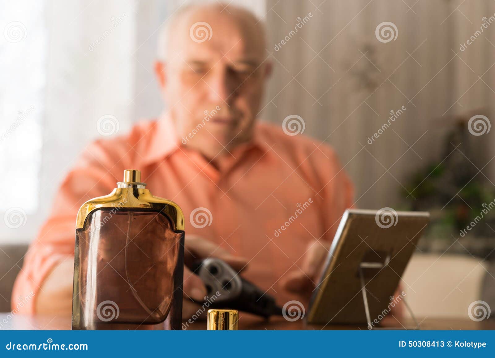 aftershave bottle in front old bald man