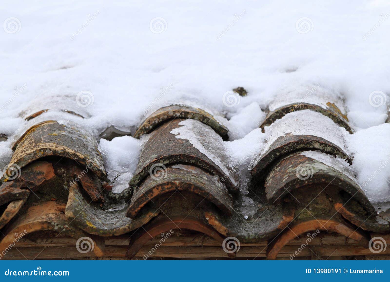 aged clay roof tiles snowed under winter snow