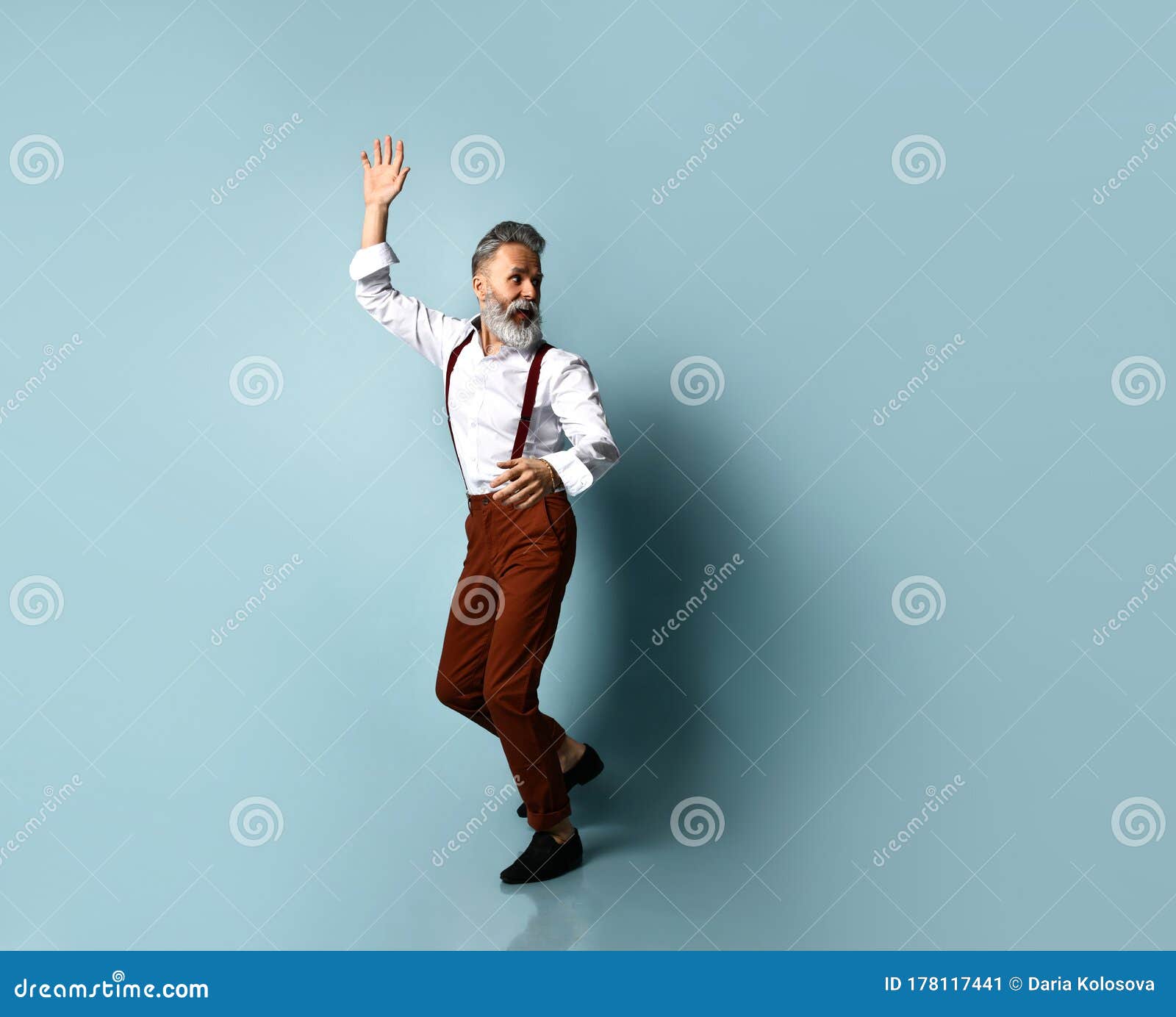 Grayhaired Male in White Shirt Brown Pants Suspenders Black Loafers he  Runs Looking Back Posing Sideways on Blue Background Stock Image  Image  of modern male 178085207