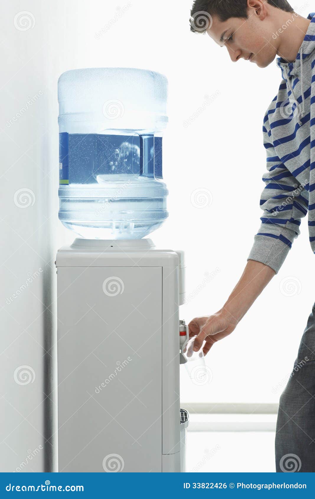 Agua de colada del hombre del refrigerador. Vista lateral de un agua de colada del hombre joven del refrigerador