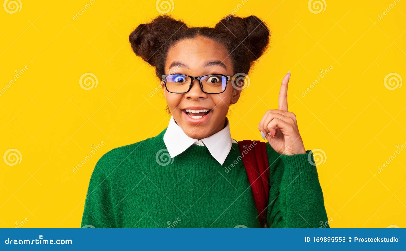 afro teenager pointing up over yellow studio wall