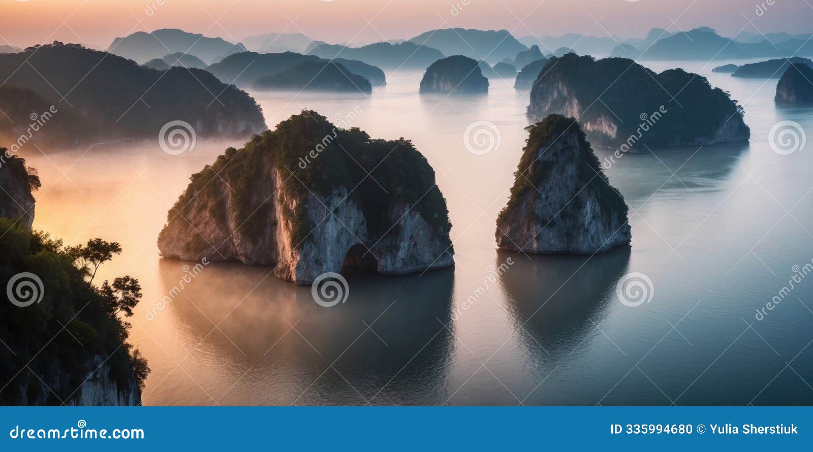 aerial predawn view of the sea bay with karst limestone islets and cliffs in morning fog.