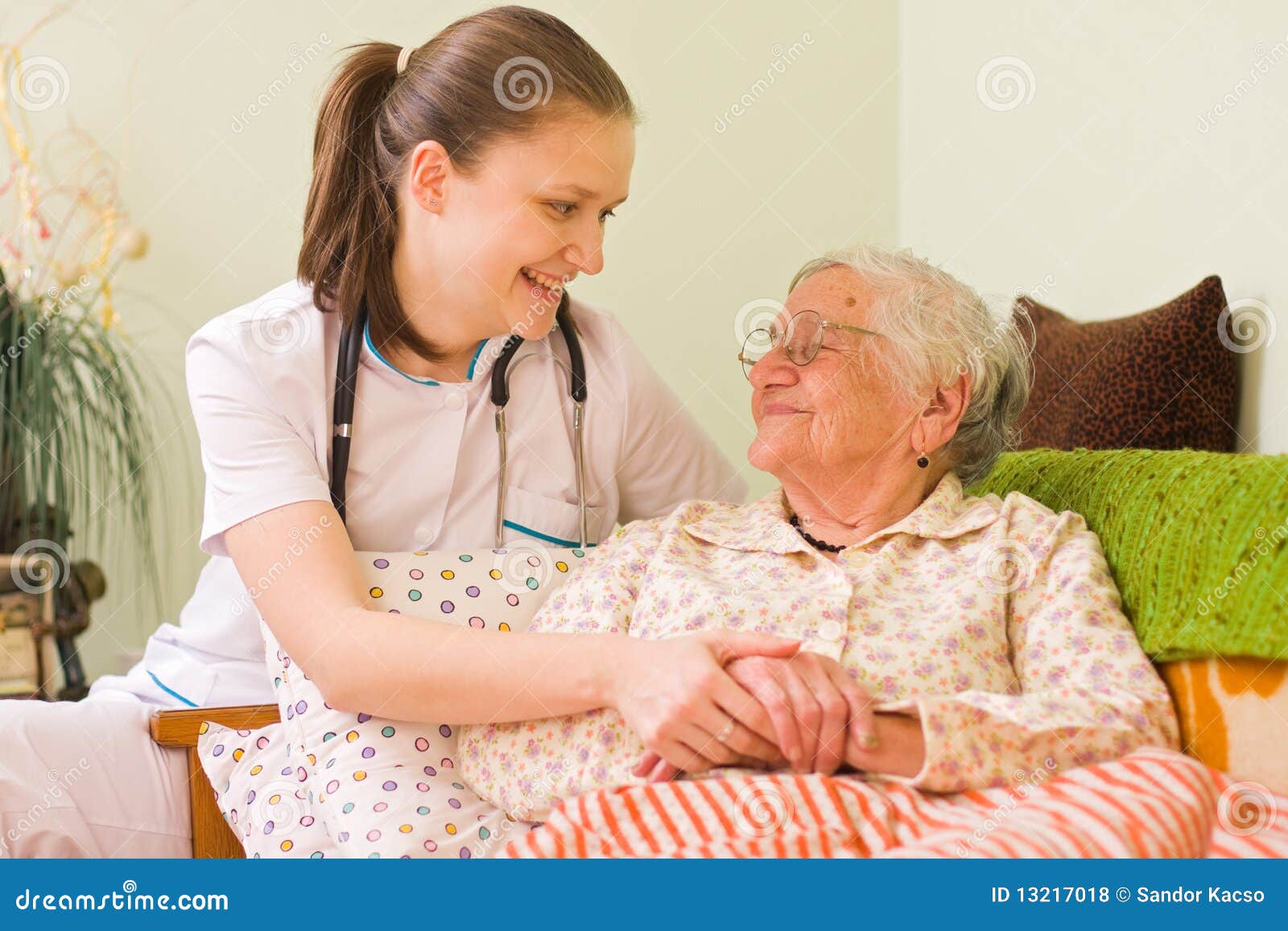 Aide d'une femme âgée malade. Un jeunes médecin/infirmière rendant visite à une vieille femme malade retenant ses mains avec l'assiette de soin.