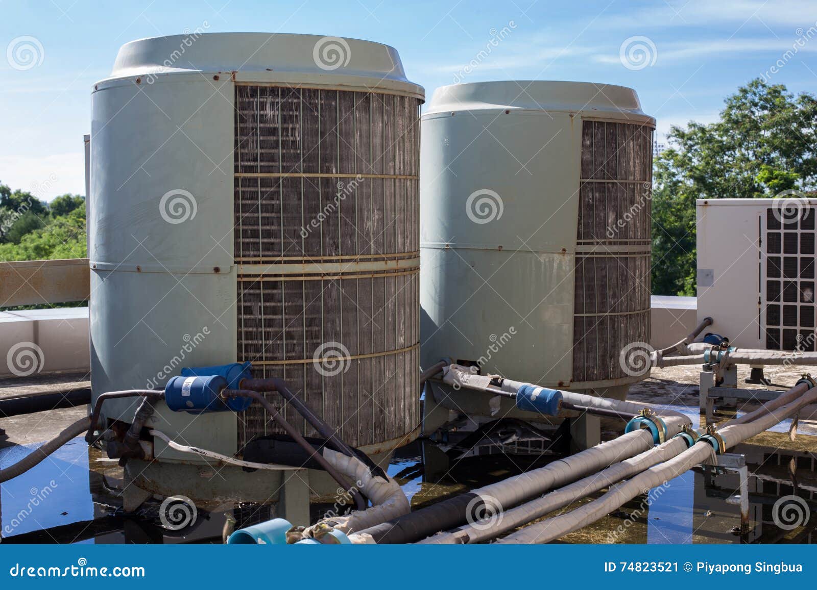 Air compressors on roof of factory with blue sky background.