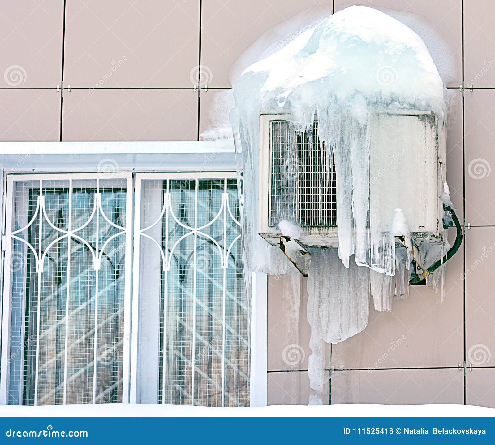 Air Conditioner Covered with Frozen Ice and Icicles. Near the Window