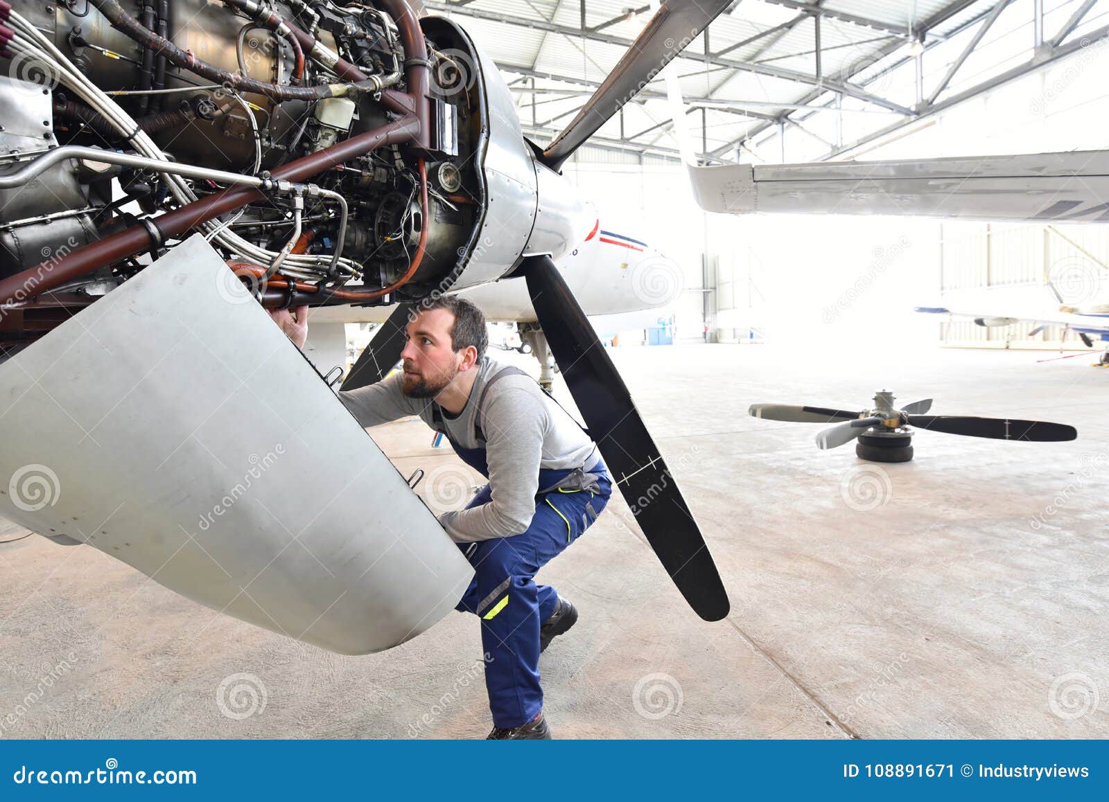 aircraft mechanic repairs an aircraft engine in an airport hangar