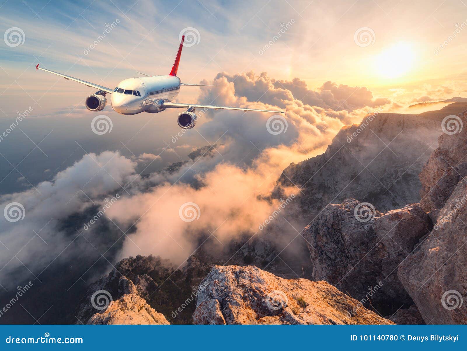 landscape with white passenger airplane, mountains, sea and orange sky