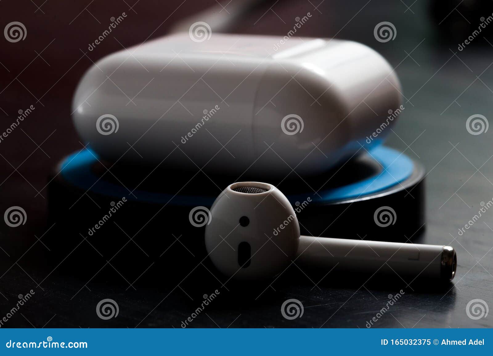 Airpod with Charging Case on Wireless Charger in Low Key Lighting Stock