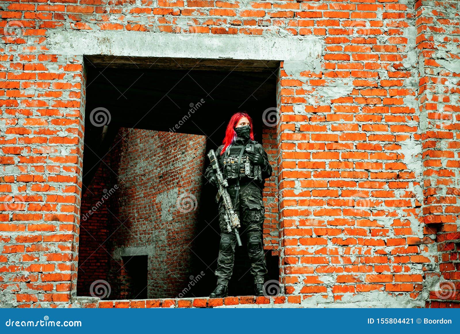airsoft red-hair woman in uniform with machine gun standing on ruins