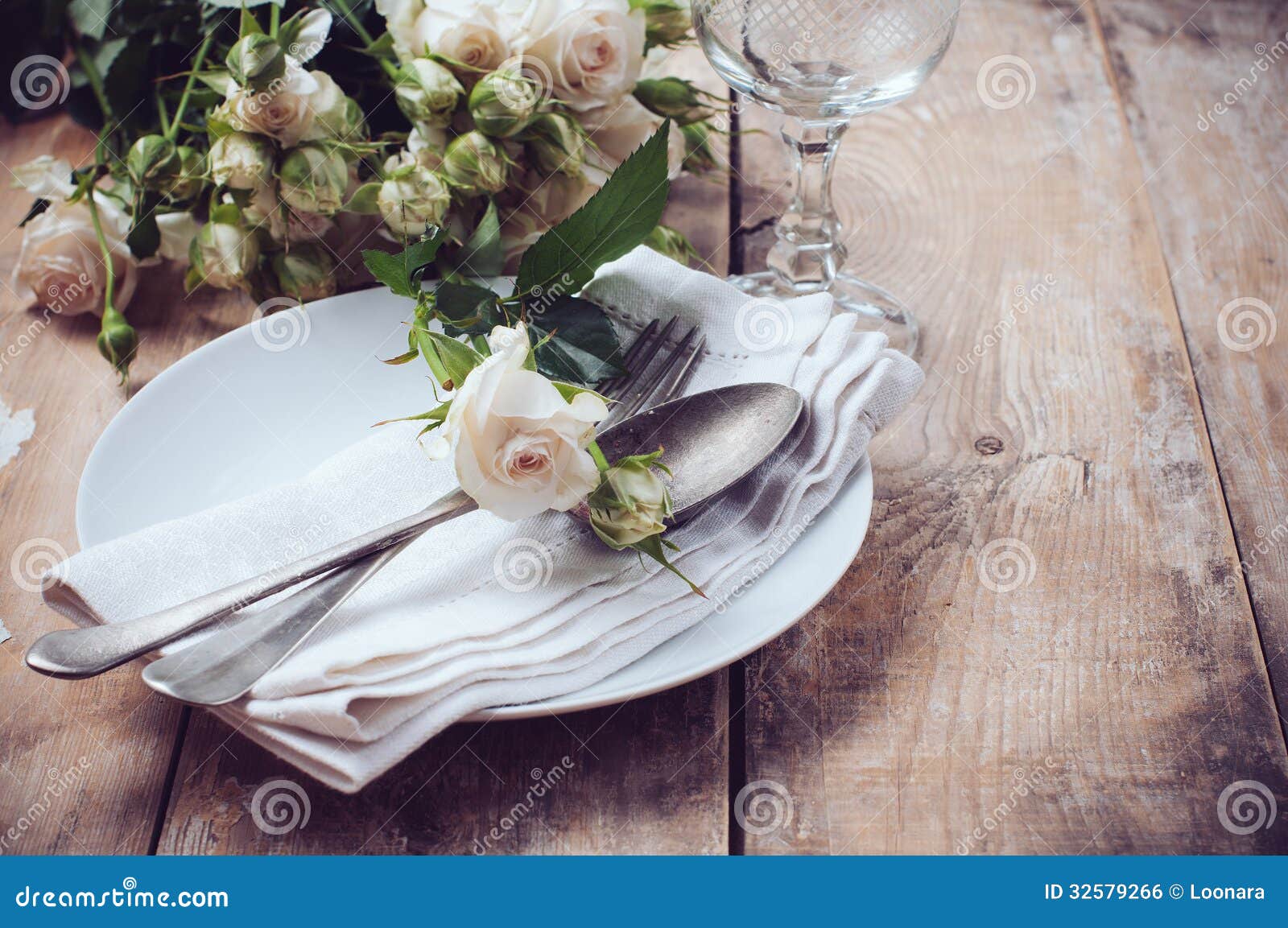 Ajuste de la tabla del vintage con las rosas, los platos rústicos antiguos y los cubiertos en el fondo de madera, primer