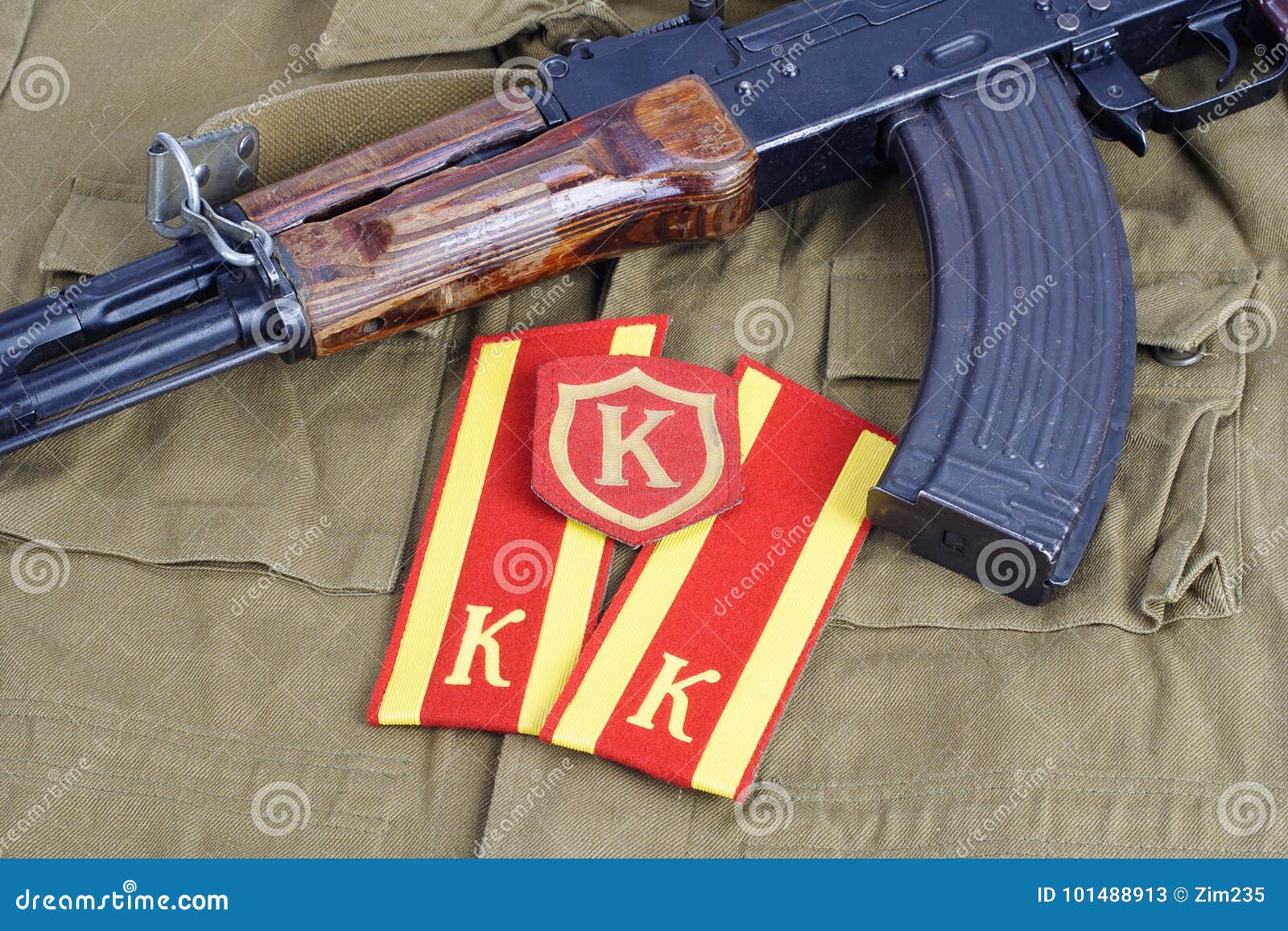 ak 47 with soviet army cadet shoulder mark and commandant shoulder patch on khaki uniform background