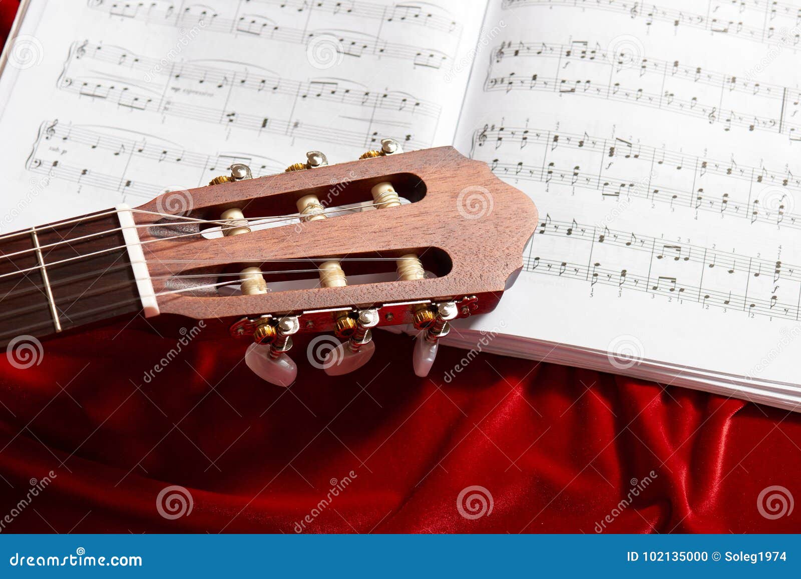 Akoestische gitaar en muzieknota's over rode fluweelstof, dichte mening van voorwerpen