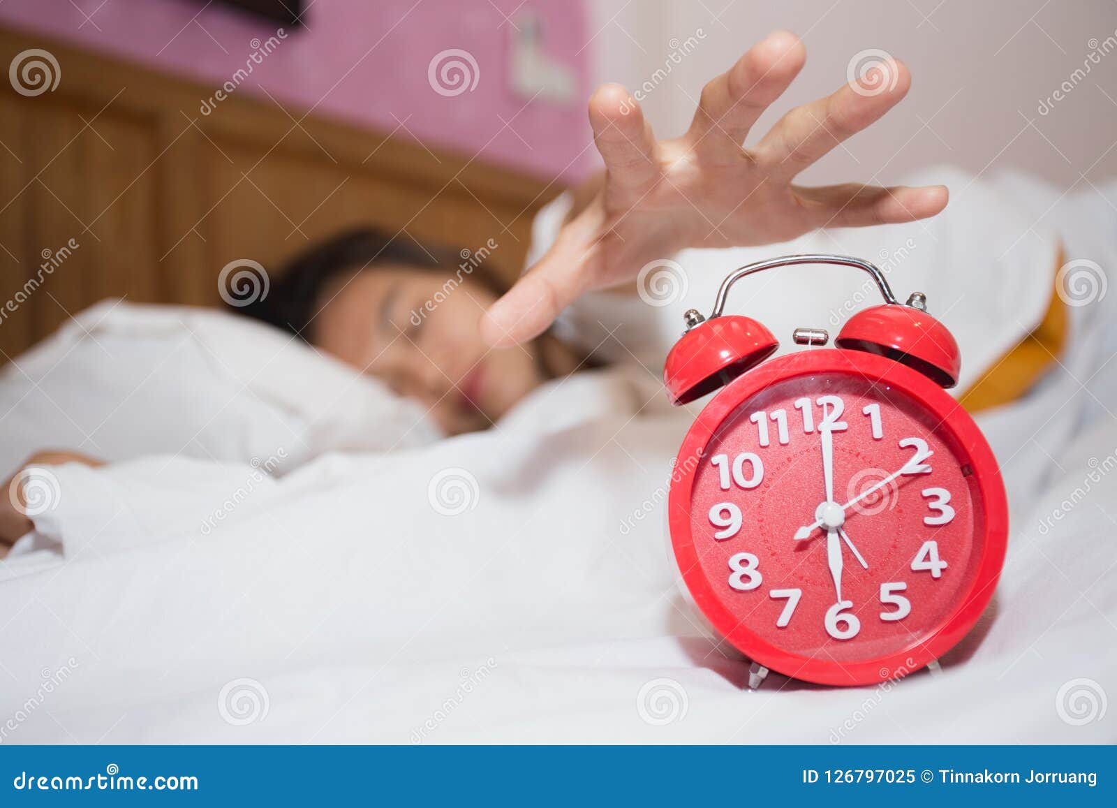 Alarm Clock in Bedroom with Lazy Woman Sleeping Trying To Stop Stock