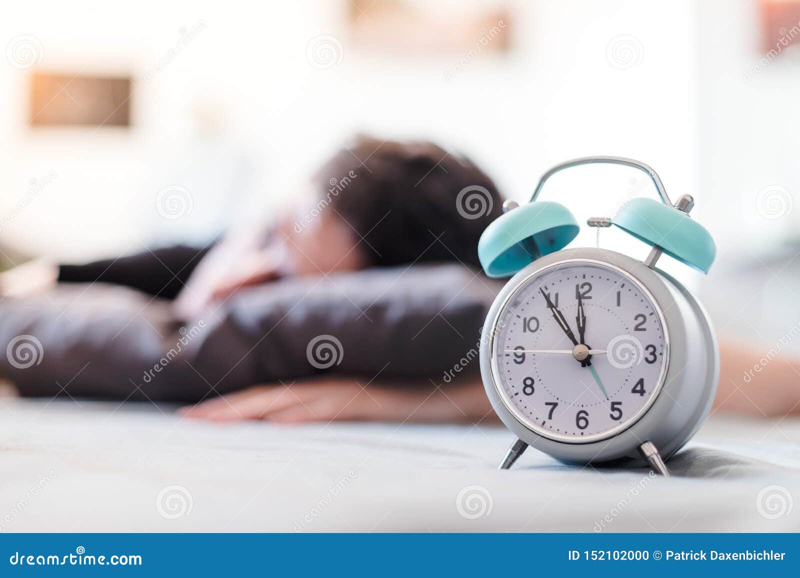 Alarm Clock in the Morning. Young Man Sleeps in the Blurry Background